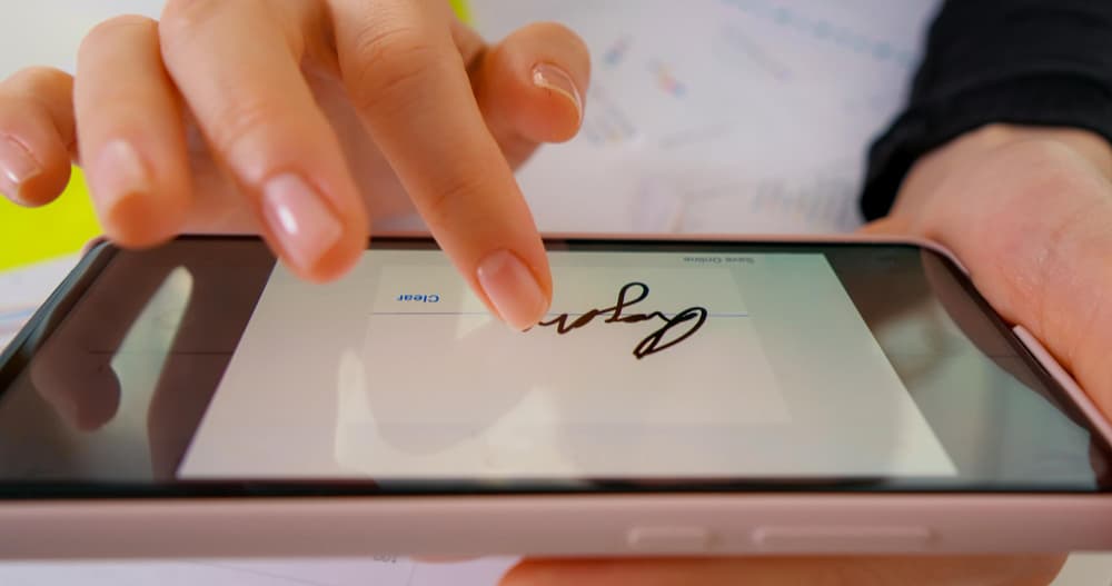 une personne appose sa signature sur une tablette numérique