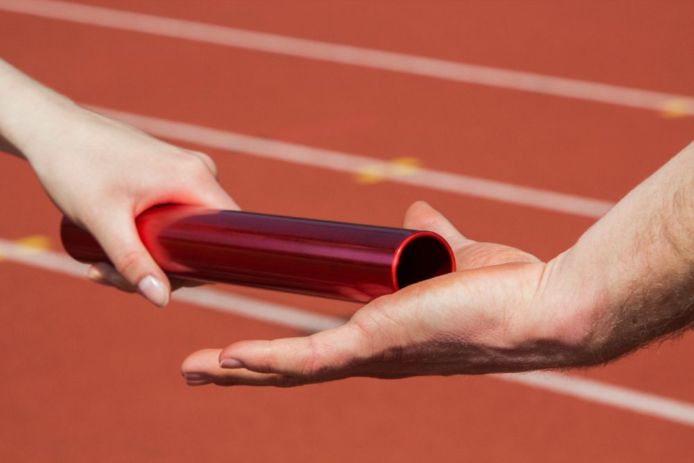 Passation d'un témoin rouge lors d'une course de relais sur une piste d'athlétisme