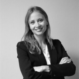 Portrait noir et blanc de Katsiaryna Lucas, souriante, en blazer noir et bras croisés